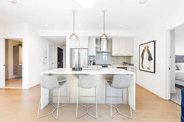 a kitchen with stainless steel appliances granite countertop a sink a stove a refrigerator and island with wooden floor