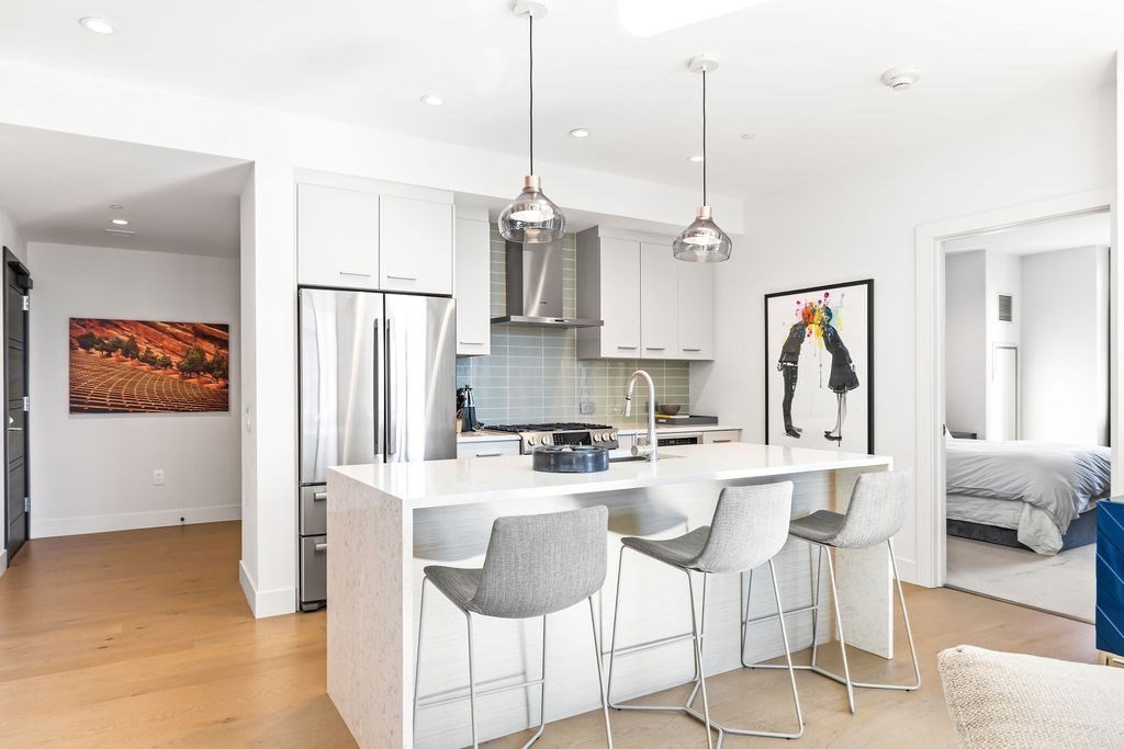 40 Traveler Street, Unit 303 Boston, MA 02118 - Photo 9 of 42 a kitchen with stainless steel appliances kitchen island granite countertop a refrigerator a stove top oven a sink dishwasher and white cabinets with wooden floor