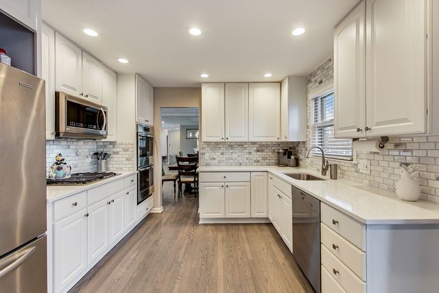 a kitchen with granite countertop a sink stainless steel appliances and white cabinets