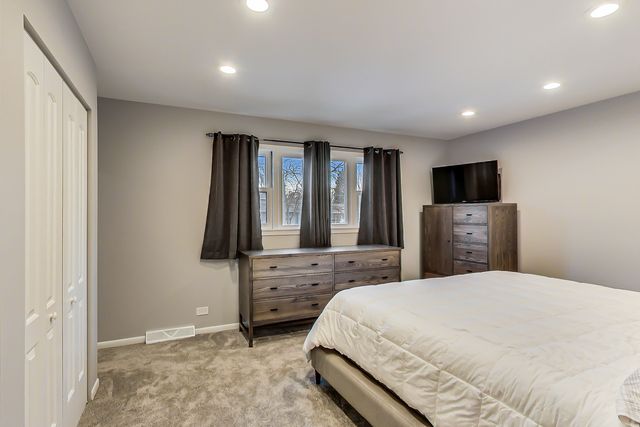 a bedroom with a large bed and a flat tv screen on a dresser