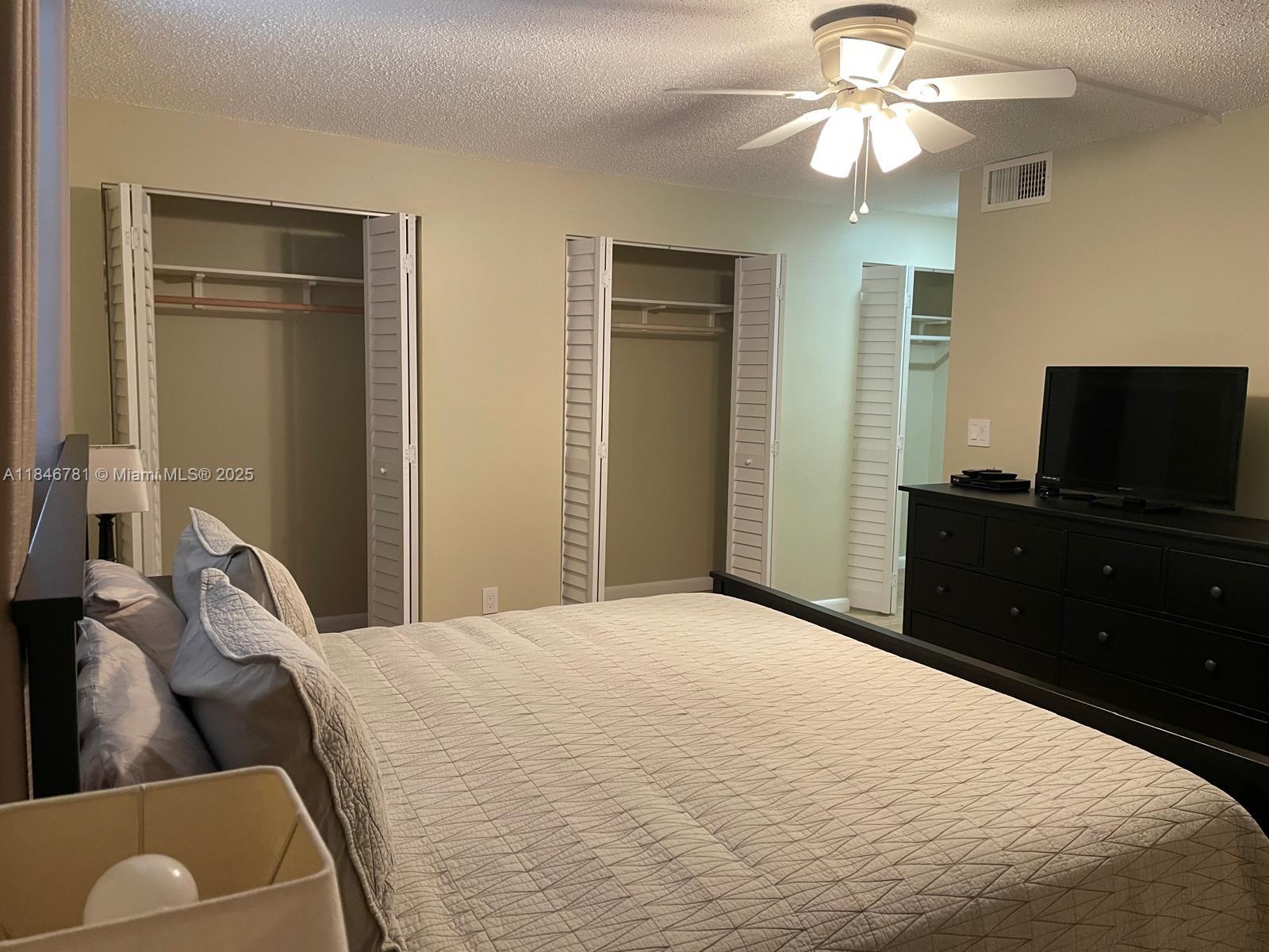 121 Southeast 3rd Avenue, Unit 201 Dania Beach, FL 33004 - Photo 15 of 49 a bedroom with a bed and a flat tv screen on dresser