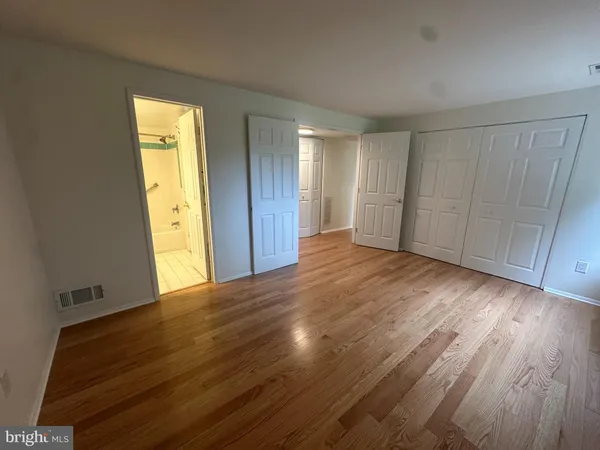 a view of an empty room with wooden floor and closet