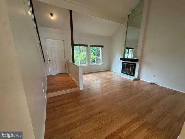 a view of a hallway with wooden floor and a kitchen