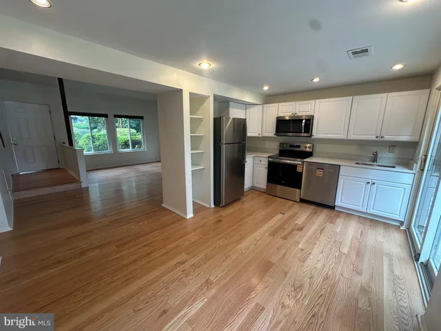 a large kitchen with stainless steel appliances granite countertop a large counter top a sink and a refrigerator