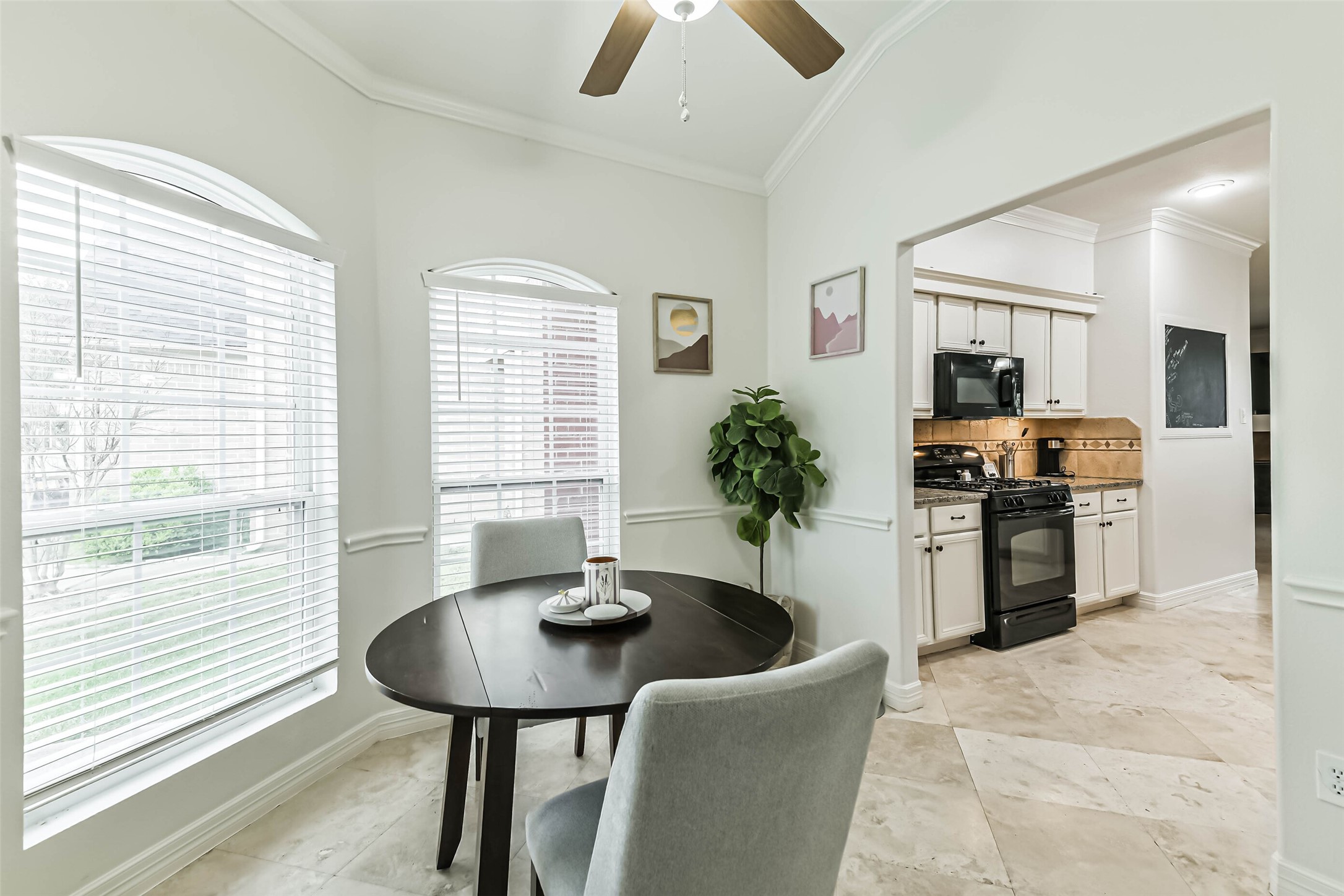 22538 Goss Spring Court Spring, TX 77373 - Photo 12 of 36 This cozy dining nook features large windows for natural light, a round table with cushioned chairs, and a view into a modern kitchen with white cabinetry and a black stove. Neutral tones and tile flooring enhance the inviting atmosphere.