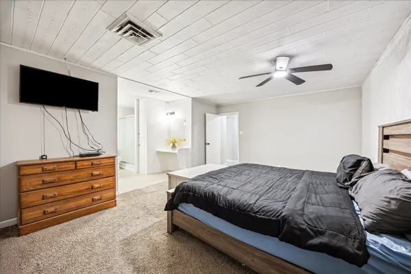 a bedroom with a bed a flat screen tv and dresser