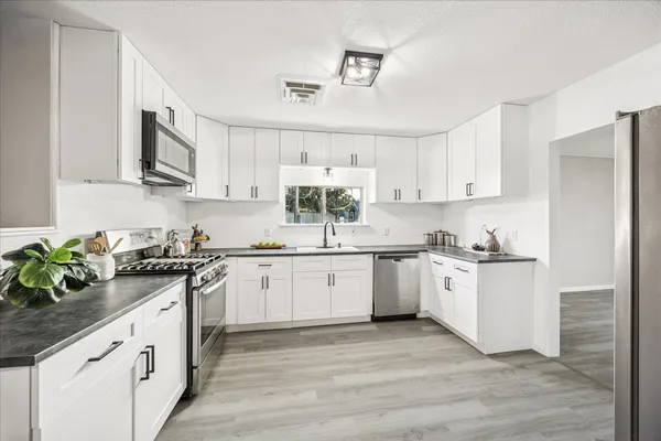 a kitchen with stainless steel appliances granite countertop white cabinets a stove a sink and dishwasher