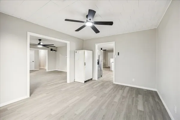 a view of empty room with wooden floor and ceiling fan