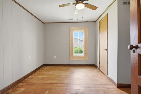 an empty room with a chandelier fan and windows