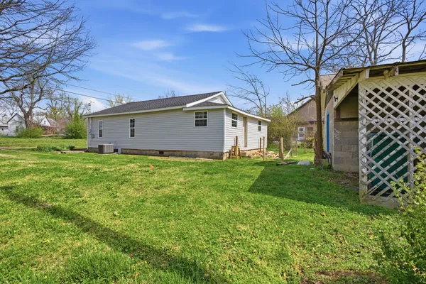 a view of a house with a big yard and large tree