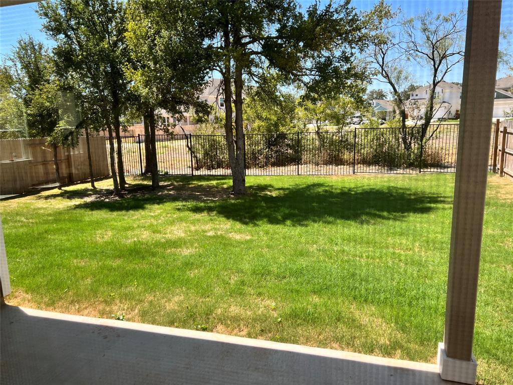 128 Free Stone Drive Georgetown, TX 78628 - Photo 29 of 29 Expansive backyard featuring a manicured lawn, established trees, and a black wrought iron fence