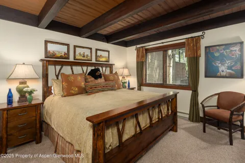 a bedroom with a bed a desk and chair with a large mirror next to a window