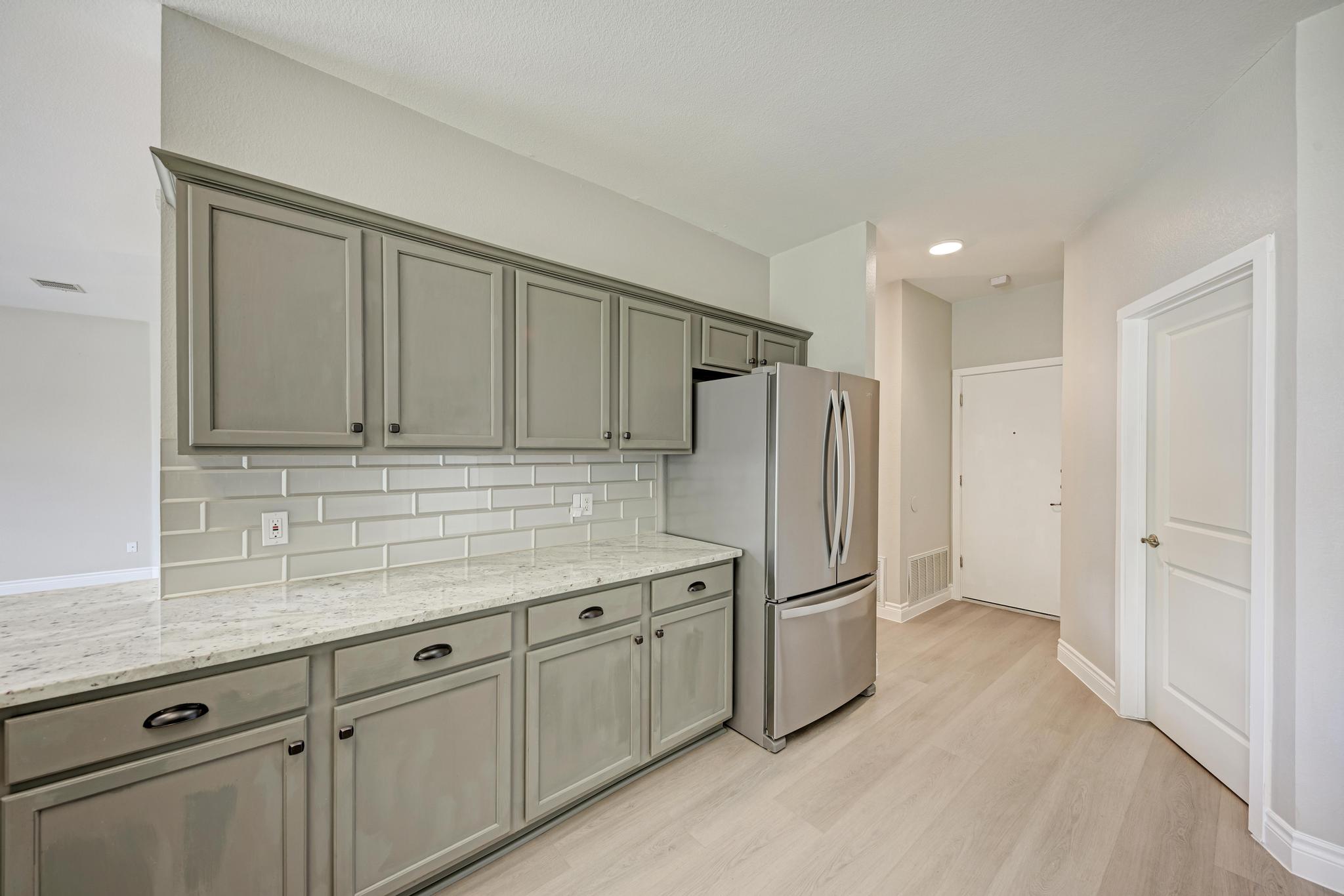 4408 Tello Path Austin, TX 78749 - Photo 18 of 38 Kitchen with freestanding refrigerator, decorative backsplash, light wood-type flooring, and light stone counters