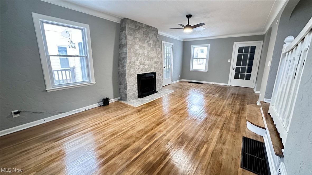 1914 Seneca Road Euclid, OH 44117 - Photo 8 of 30 Unfurnished living room featuring ornamental molding, wood finished floors, baseboards, ceiling fan, and a large fireplace