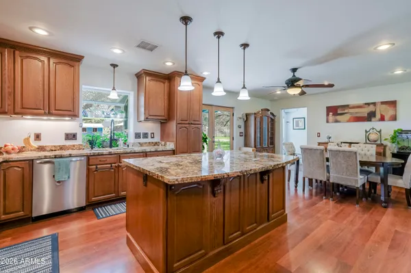 a kitchen with stainless steel appliances granite countertop wooden floors wooden cabinets a stove and a center island