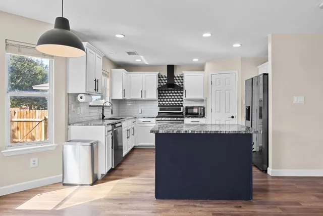 a kitchen with stainless steel appliances granite countertop a sink a stove and a refrigerator