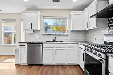 a kitchen with stainless steel appliances granite countertop a sink stove and cabinets