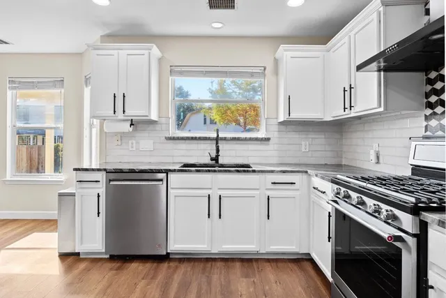 a kitchen with stainless steel appliances granite countertop a sink stove and cabinets