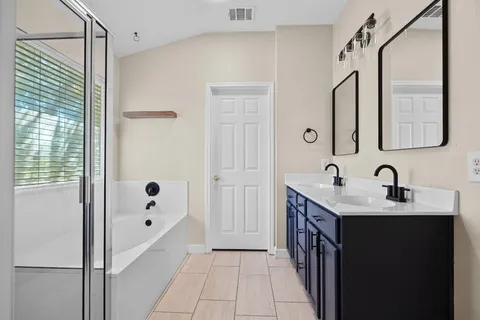 a bathroom with a double vanity sink a mirror and a bathtub
