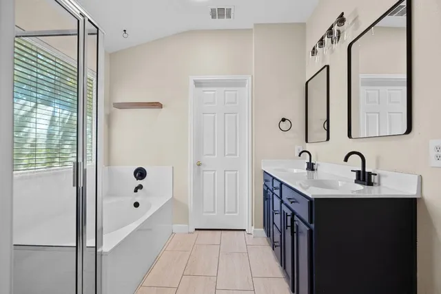 a bathroom with a double vanity sink a mirror and a bathtub