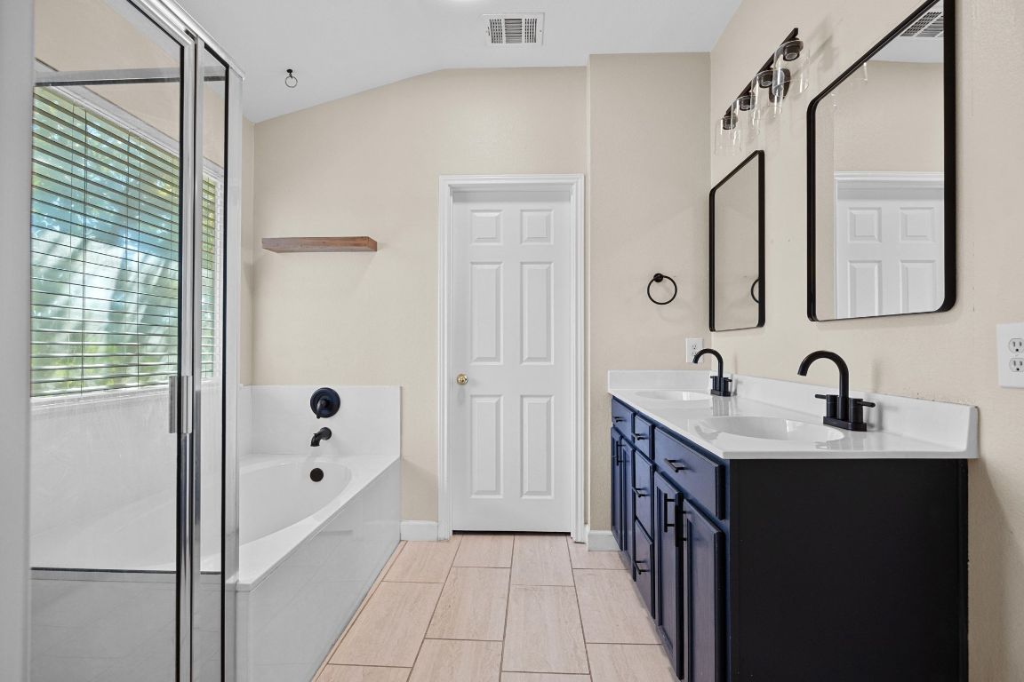 1405 Ty Cobb Place Round Rock, TX 78665 - Photo 23 of 33 a bathroom with a double vanity sink a mirror and a bathtub