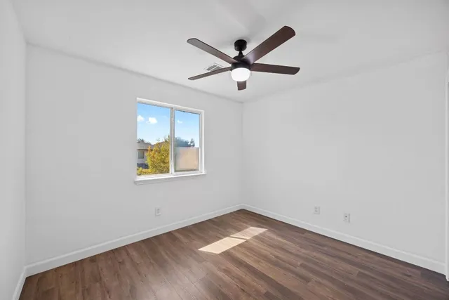 a view of empty room with wooden floor and fan
