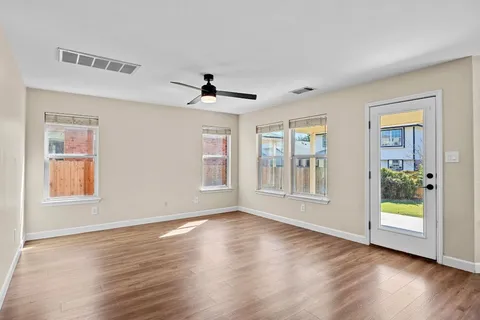 a view of an empty room with a window and wooden floor