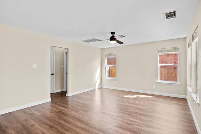 a view of an empty room with wooden floor and a window
