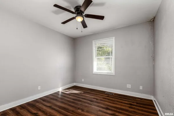 an empty room with wooden floor cabinet and windows