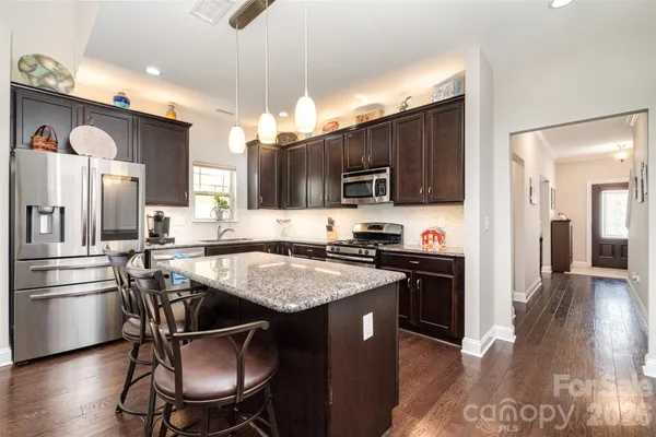 a kitchen with kitchen island granite countertop a sink cabinets and stainless steel appliances
