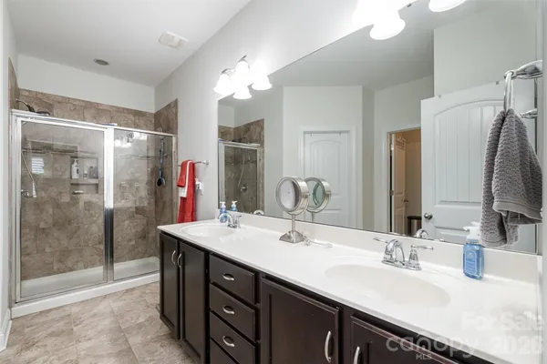 a bathroom with a double vanity sink mirror and shower