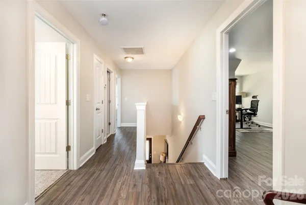 a view of a hallway with wooden floor and stairs
