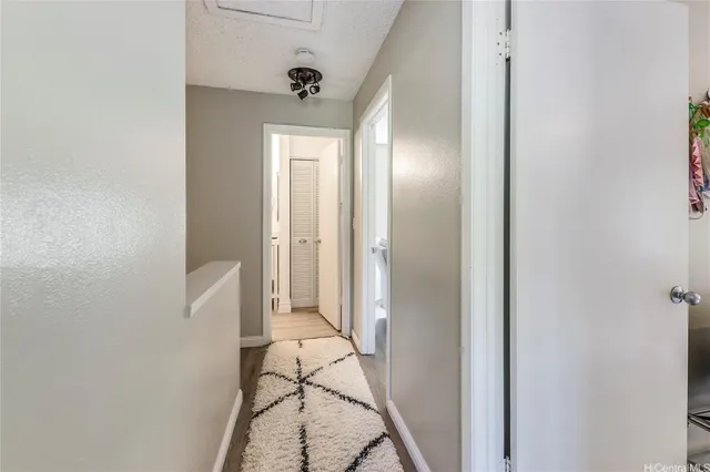 a view of a hallway with wooden floor and a bathroom