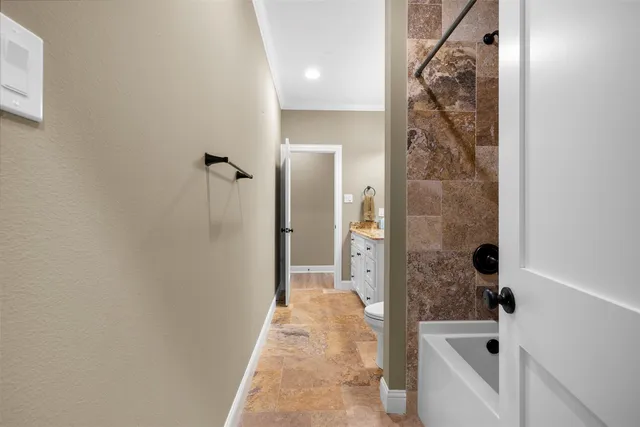 a view of a hallway with wooden floor and a bathroom