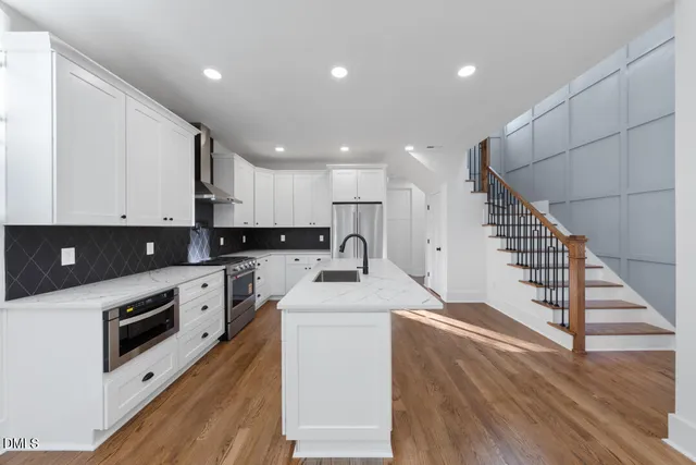 a large kitchen with stainless steel appliances granite countertop a stove a sink dishwasher and a refrigerator with wooden floor