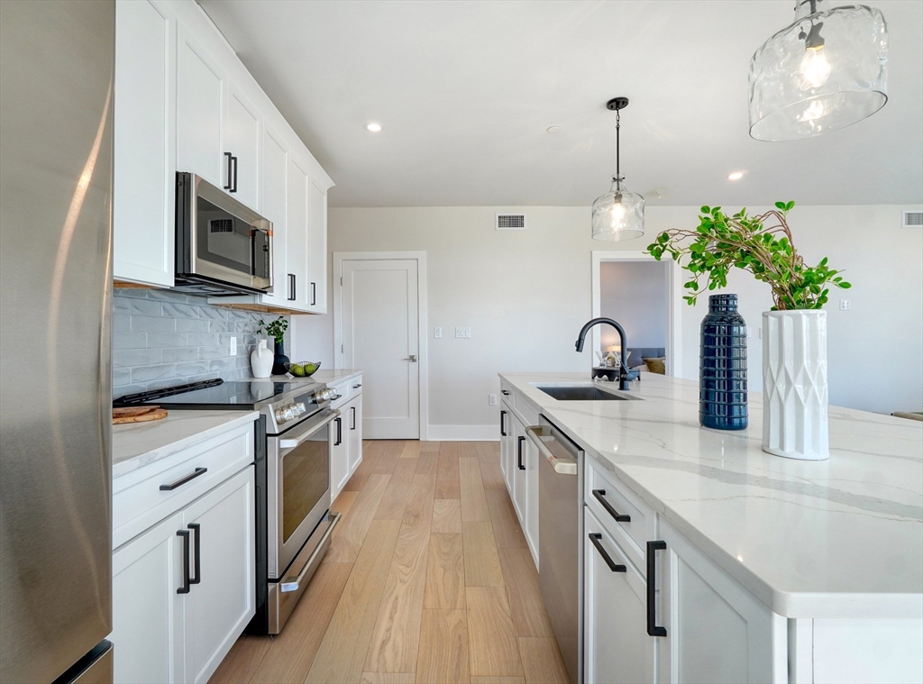 62 Foundry Street, Unit 415 Wakefield, MA 01880 - Photo 21 of 42 a kitchen with stainless steel appliances a sink stove and microwave