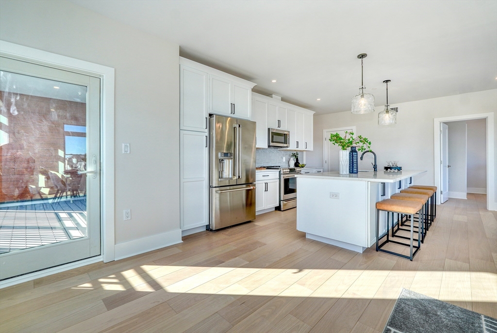 62 Foundry Street, Unit 415 Wakefield, MA 01880 - Photo 6 of 42 a living room with stainless steel appliances kitchen island granite countertop a refrigerator a stove a sink a dining table and chairs