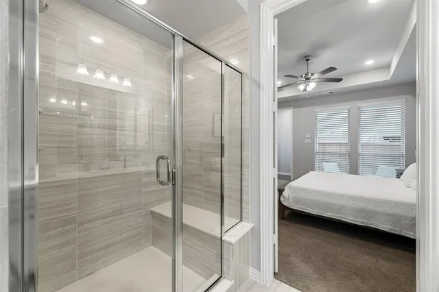 a bathroom with a bed and a glass door shower