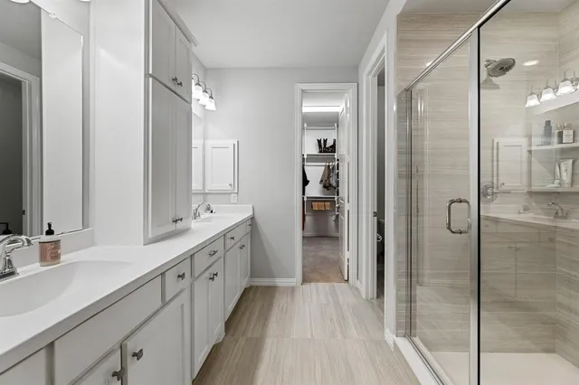 a spacious bathroom with a double vanity sink a mirror and shower