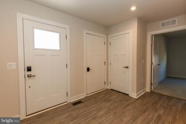 a view of an empty room with wooden floor and closet