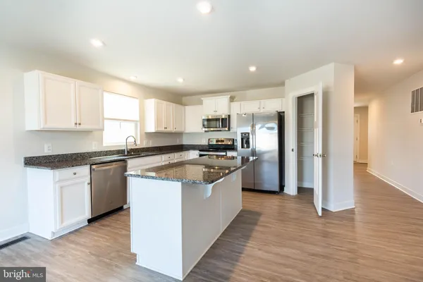 a large kitchen with stainless steel appliances granite countertop a stove a sink and a refrigerator
