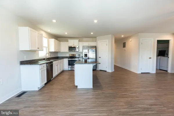 a kitchen with stainless steel appliances granite countertop a stove top oven a sink and a refrigerator