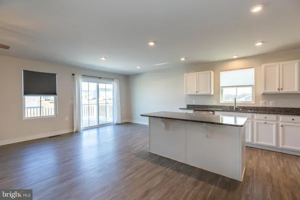 a large kitchen with stainless steel appliances granite countertop a stove a sink and white cabinets with wooden floor next to windows