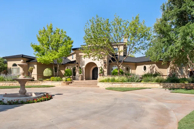 a front view of a building with garden and trees