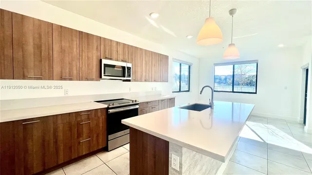 a kitchen with stainless steel appliances wooden cabinets a stove a sink and a microwave