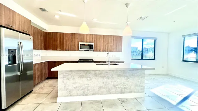 a large kitchen with kitchen island granite countertop a sink a counter top space and cabinets