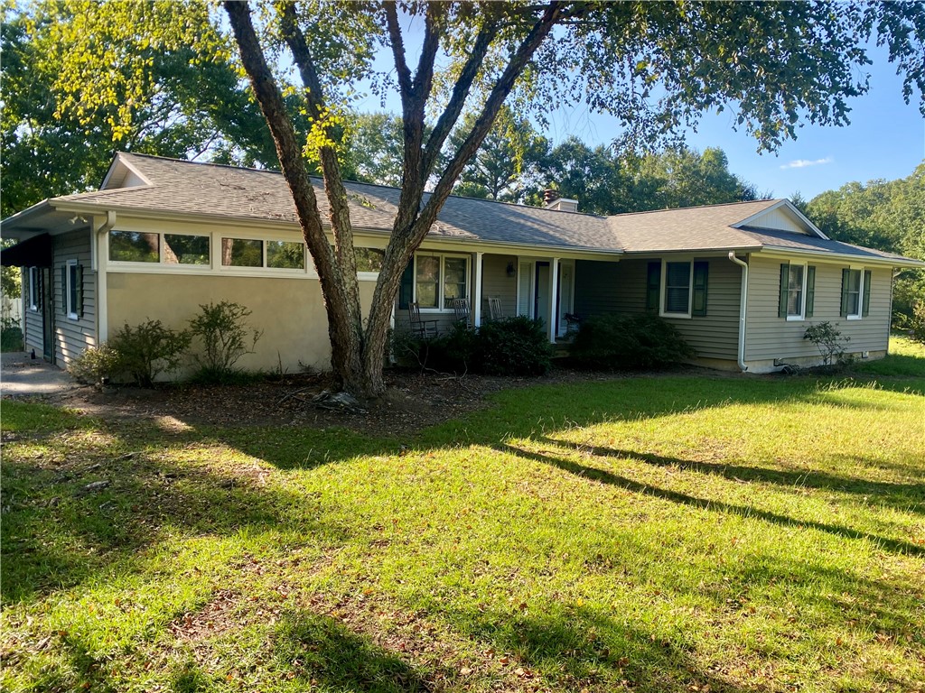 Mature trees shade a classic single-story ranch home set on a grassy lawn.