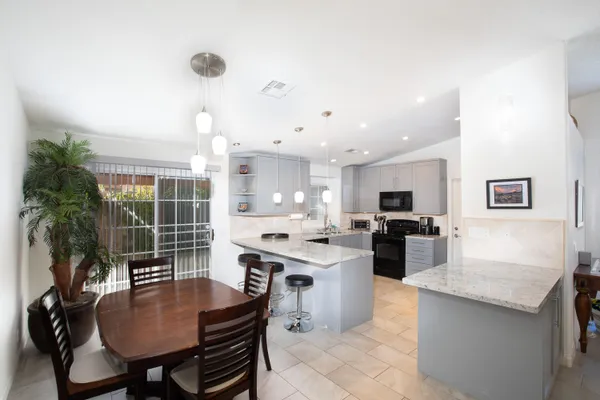 a open kitchen with kitchen island a stove a sink a dining table and chairs with wooden floor