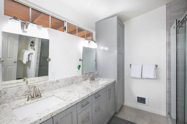 a bathroom with a granite countertop double vanity sink and mirror