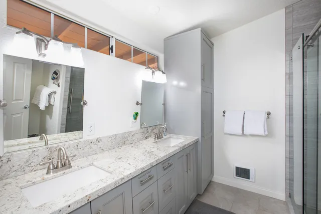 a bathroom with a granite countertop double vanity sink and mirror